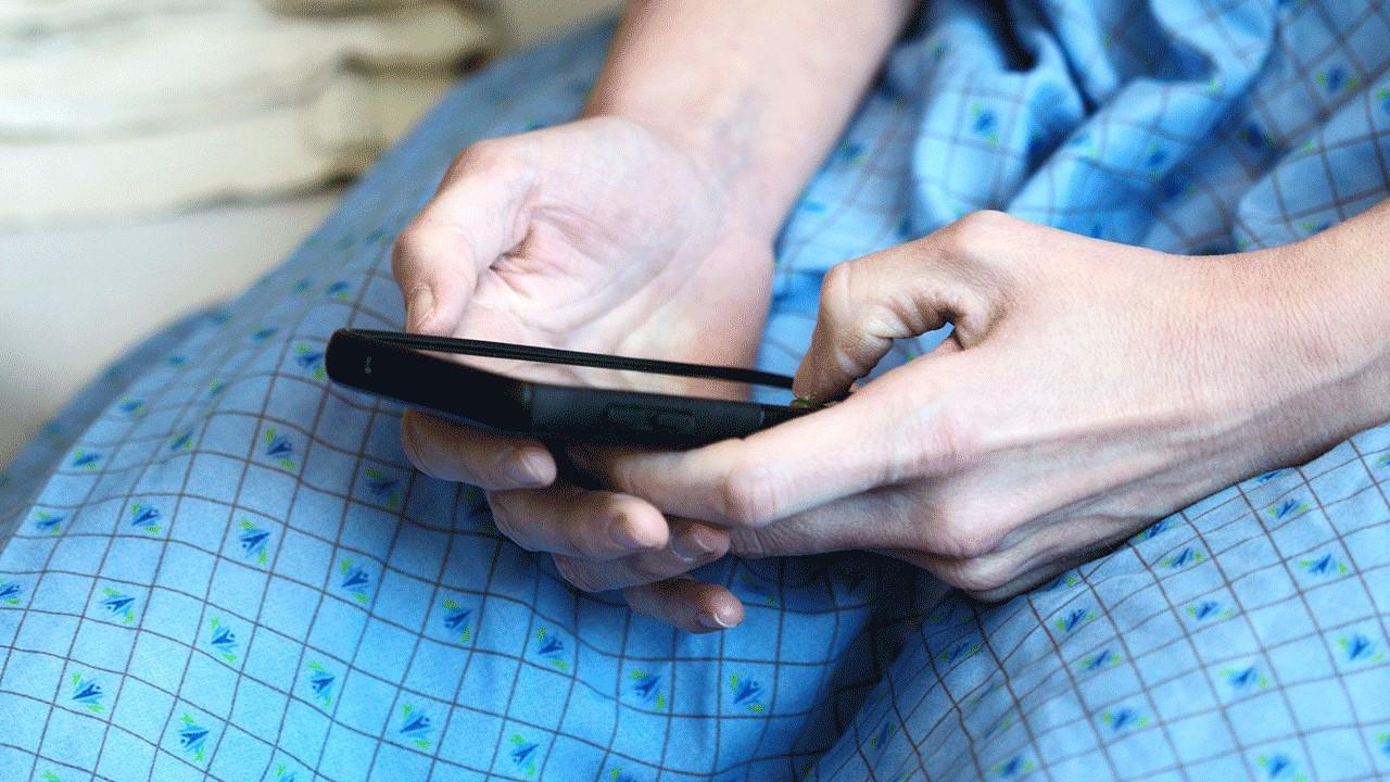 Mani di un paziente che tengono un cellulare