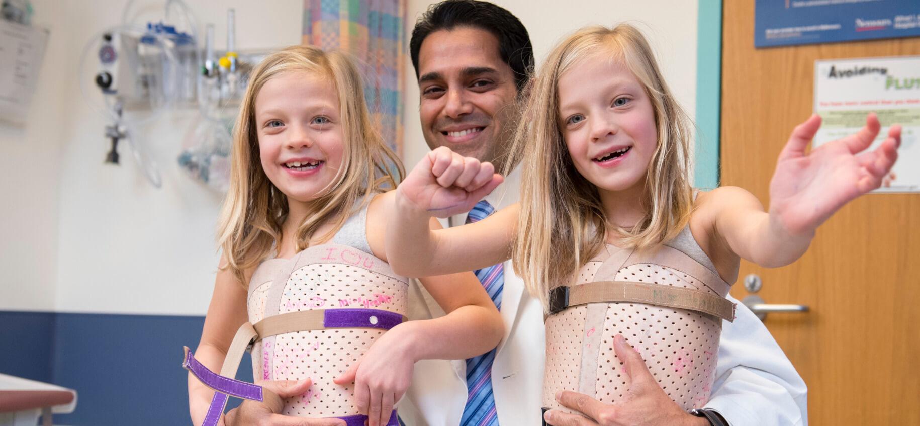 2 orthopaedic children with a doctor wearing spinal corrective medical devices