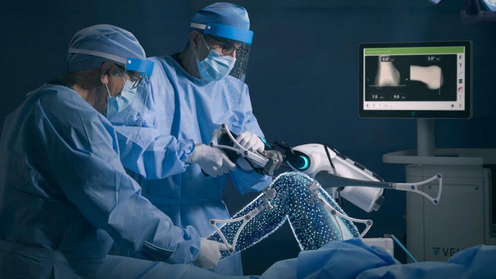 Orthopaedic surgeons performing knee replacement surgery with assistance of robot