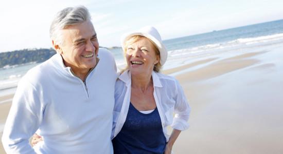 Senior couple laughing and walking on beach